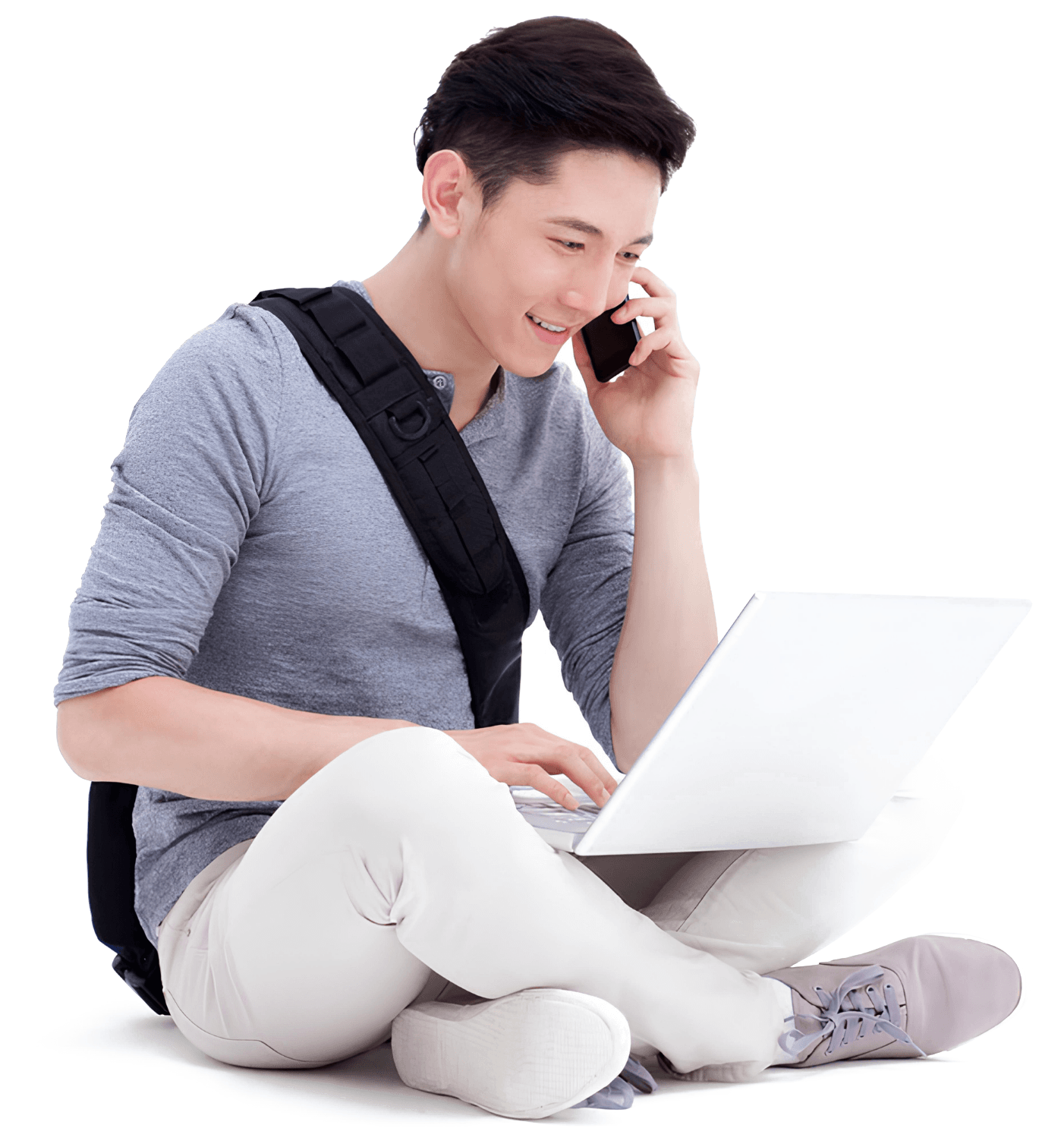 A student working on a laptop while talking on the phone